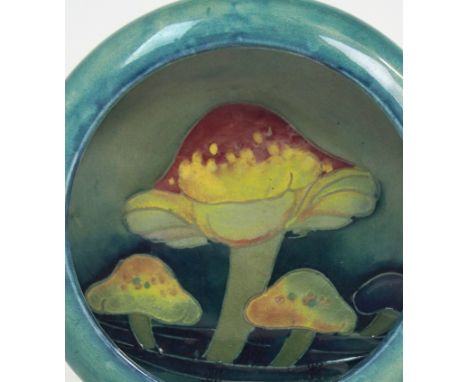 A MOORCROFT CLAREMONT PATTERN DISH the blue/green ground decorated with toadstools in yellow and red, with impressed marks to