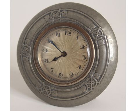 A TUDRIC PEWTER CLOCK the engine turned dial with Arabic numerals, the pewter case with stylized decoration, the back stamped