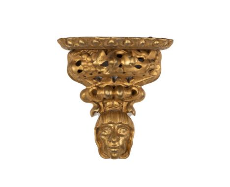 A Florentine gilt wall bracket, the shelf above pierced foliate support with mask below, 29.5cm wide x 31.5cm high