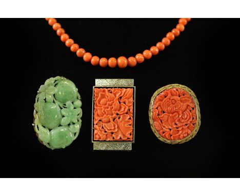 A carved jade brooch modelled as pumpkins, in an oval frame marked 'silver', 53mm wide, a carved coral plaque brooch, the sil