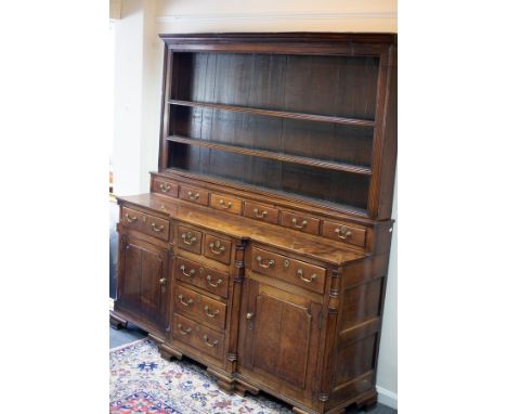 A Georgian oak Welsh dresser, the rack above six spice drawers upon a base of five small drawers above cupboard doors flankin