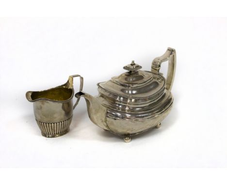 A George III silver teapot, SH, London 1815 and a cream jug with half-ribbed decoration, London 1800, approximately 844gm