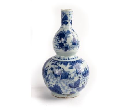 A Chinese blue and white double gourd vase, Transitional period, decorated figures within garden settings, a band of stiff le