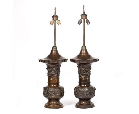 A PAIR OF BRONZE TABLE LAMPS in the Oriental style decorated with dragons and fruiting branches, the serpentine tops to the v