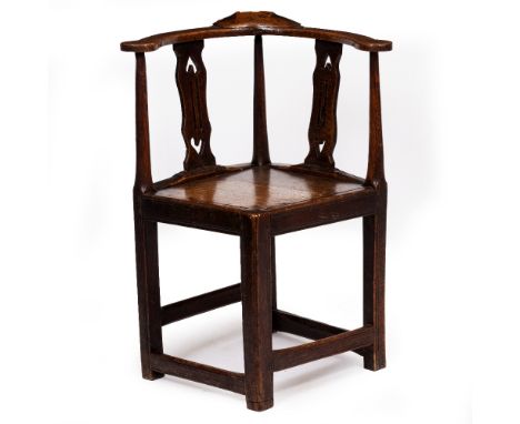 AN ANTIQUE PRIMITIVE OAK CORNER ARMCHAIR with pierce splats, panel seat and the reeded legs united by stretchers, 16cm wide a