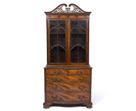 A GEORGE III STYLE MAHOGANY BOOKCASE with pierced fretwork swan neck pediment, astragal glazed doors enclosing adjustable she