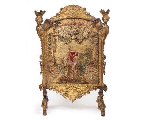 A DECORATIVE GILT FIRE SCREEN the finials in the form of female heads with plumed head dresses, with a frame decorated with c