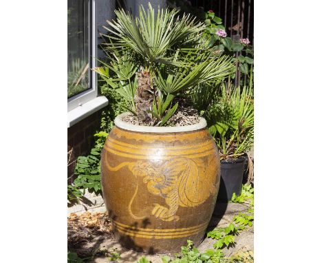 A LARGE ORIENTAL STONE WARE OVOID PLANTER decorated with a dragon and complete with small palm, the jar 60cm diameter x 71cm 