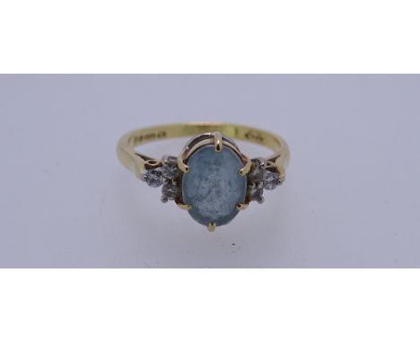 AN 18CT GOLD DRESS RING with a cluster of oval blue quartz and three tiny flanking diamonds either side, 3.4grms, size M