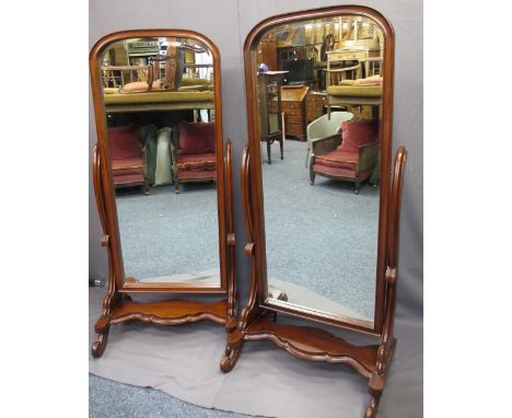 REPRODUCTION MAHOGANY CHEVAL MIRRORS, a pair, arched top frames and bevel edged mirrors on shaped and carved supports and pla