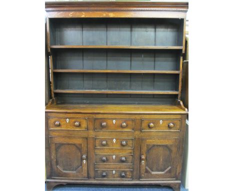 NORTH WALES ANGLESEY OAK DRESSER, CIRCA 1830, the wide boarded back three shelf rack with shaped detail to the cornice over a