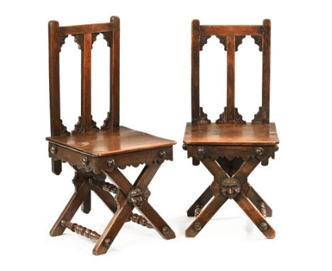 A pair of 19th century oak hall chairs, having slat and bracket backs with solid seats on Green Man crest bobbin and X frame 