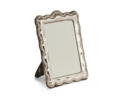 A silver framed mirror, bevelled plate with repousse border London mark 1968.  Overall dimensions 29 cm x 22 cm, easel back.