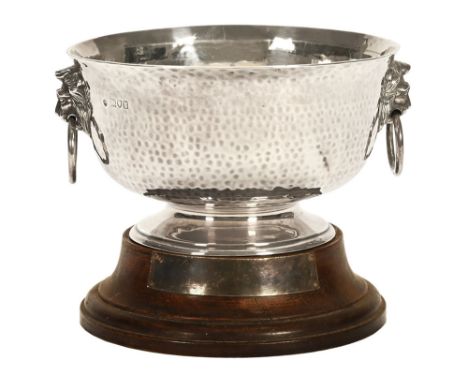 A round silver bowl, with hammered decoration and two lion mask handles, London 1912.  15.5 cm high, to include plinth, +/- 4