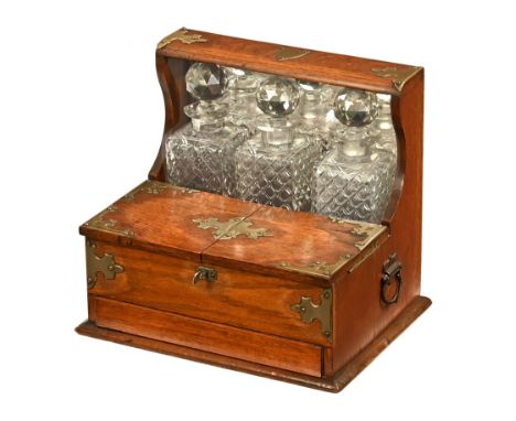 A late Victorian oak cased tantalus and games box, of traditional design with silvered metal applique with mirror back and th
