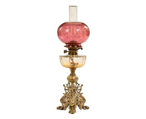 A late 19th/early 20th century oil lamp, with later etched cranberry glass shade over a glass reservoir and brass trefoil emb