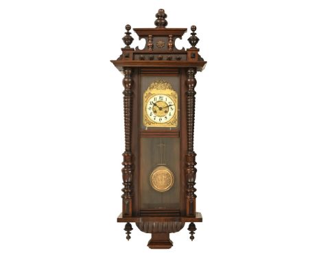 A late Victorian mahogany and stained frame Vienna wall clock, with finial top front over metal spandrel face and circular di