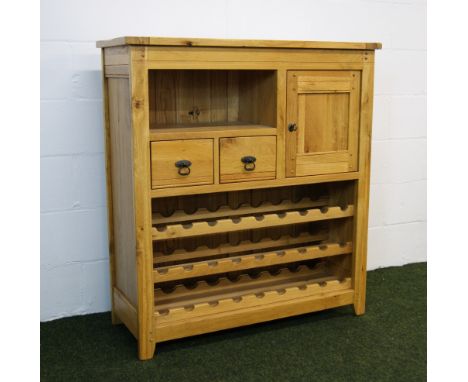 A contemporary golden oak wine stand, the rack for 27 bottles below a single-door locking cupboard, two short drawers and an 