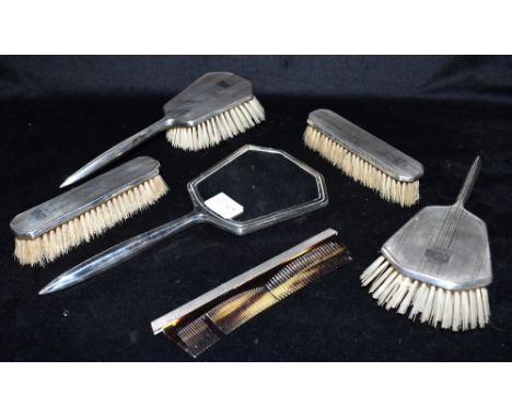 A SIX PIECE SILVER DRESSING TABLE SET comprising a mirror, a comb (a/f), two pairs of brushes, hallmarked for Birmingham, var