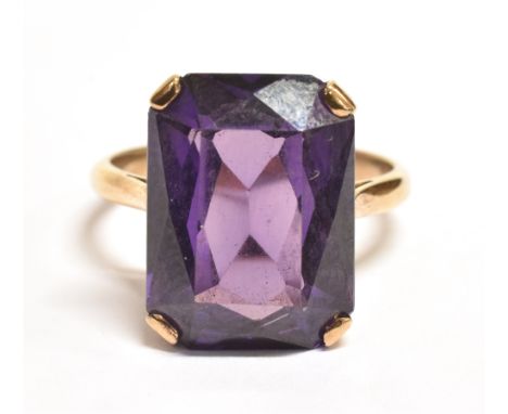 PURPLE SAPPHIRE COCKTAIL RING The single step cut stone measuring 1.6 x 1.2cm on a yellow metal shank with worn markings, rin