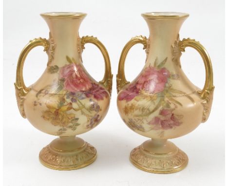 A pair of Royal Worcester blush ivory vases, printed painted with floral sprays, having gilt handles and raised on a pedestal