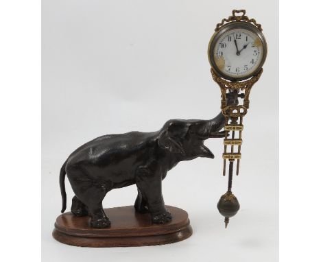 A 20th century spelter elephant mystery clock, the dial and movement incorporated into a swinging grid-iron pendulum held alo