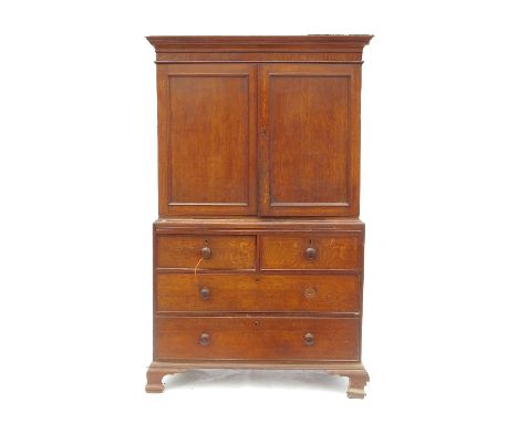 A 19th century oak linen press, having two panelled doors to the upper section, fitted two short drawers over two long drawer