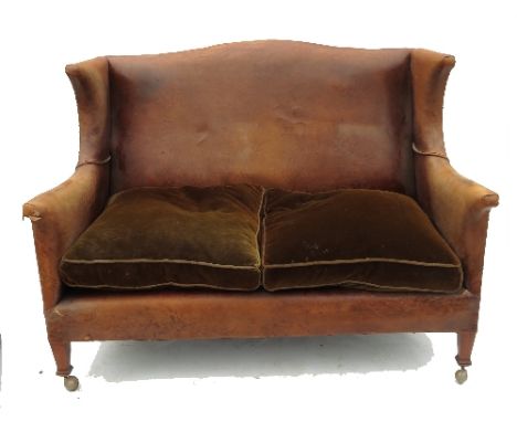 A leather upholstered two seat sofa, with wing sides and fabric cushions, width 55ins 