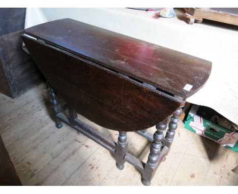 An antique oak gate leg table, raised on turned legs united by a stretcher 