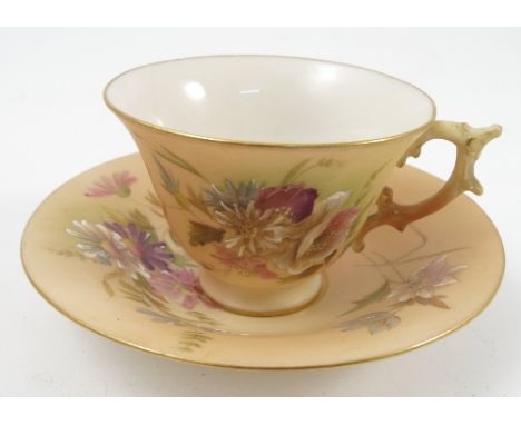A Graingers Worcester blush ivory cup and saucer, decorated with flowers, impressed mark 11J to the saucer base 