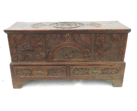 A heavily carved elm mule chest, having a carved rising lid, heavily carved front and two drawers below, width 47.5ins 