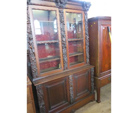 An oak display cabinet, the upper section fitted with glazed doors opening to reveal shelves, the base fitted with cupboard d