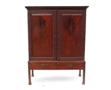 A mahogany cupboard on stand, having two panelled doors with blind fret carved borders opening to reveal shelves and tray, ra