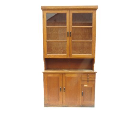 Two similar oak cupboards, fitted with a pair of doors flanked by six narrow short drawers over further door, the one having 
