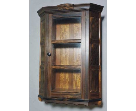 Oliver Morel - a Macasar ebony corner cupboard with flared cornice centred on a shaped tablet the triple glazed door flanked 