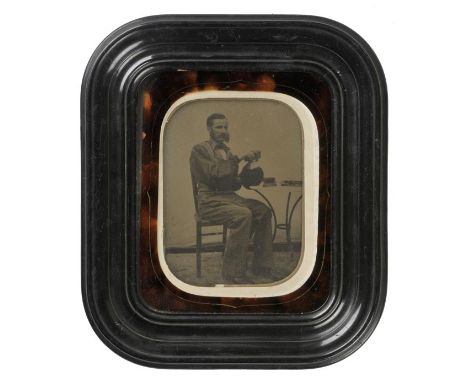 *Ambrotypes. A large half-plate ambrotype of a hatmaker, circa 1855,  full length, seated, period tortoiseshell and ebonised 