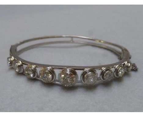 A diamond and white metal bangle approx 4 1/2 cts, the centre stone measuring 7mm flanked by eight matched graduating stones,