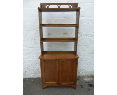 An Arts & Crafts light oak bookcase cupboard with fretwork gallery, of slim proportions. 