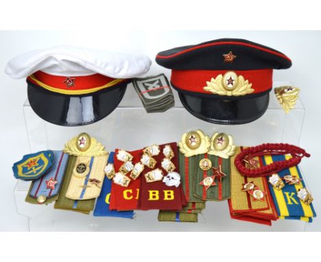 A quantity of Russian militaria-related items to include two Soviet Red Army caps, a quantity of various epaulettes, buttons 