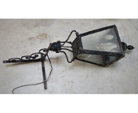 A late 19th or early 20th century painted copper and wrought iron wall-mounting street lamp, the scrolling bracket supporting