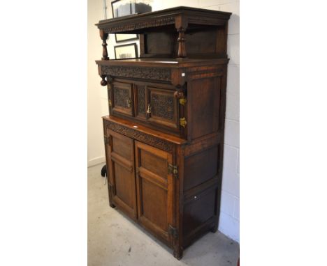 A late 17th century tridarn, profusely carved, the carved frieze over top shelf on turned supports, two cupboard doors in upp