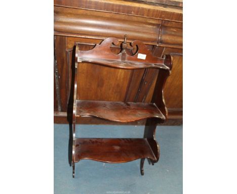 A fretworked shaped edged Mahogany wall hanging three tiered shelves with a turned and lobed finial to the top, 31 3/4" high 
