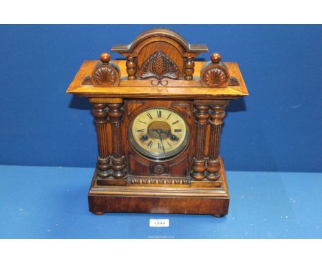 An Oak Mantle clock with pine cone detail pediment and columns, 12'' wide x 15'' high x 5 1/2' deep, with key and pendulum.