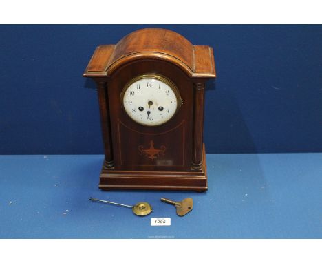 A Mahogany dome topped mantle Clock, with two train movement with Arabic numerals on a white face, flanked by two columns, 12