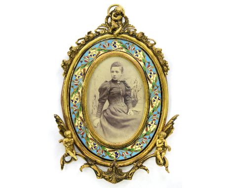 A FRENCH OVAL ORMOLU AND CHAMPLEVE ENAMEL PHOTOGRAPH FRAME, APPLIED WITH PUTTI, 26CM H, C1880 