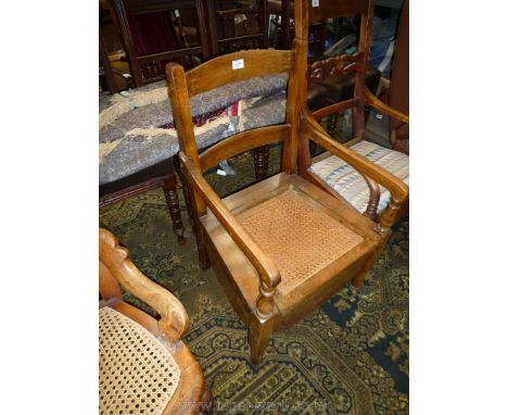 A satinwood framed, caned seated commode Armchair.
