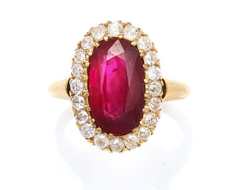 A RUBY AND DIAMOND CLUSTER RING in high carat yellow gold, set with an oval cut ruby of 3.99 carats encircled by round cut di