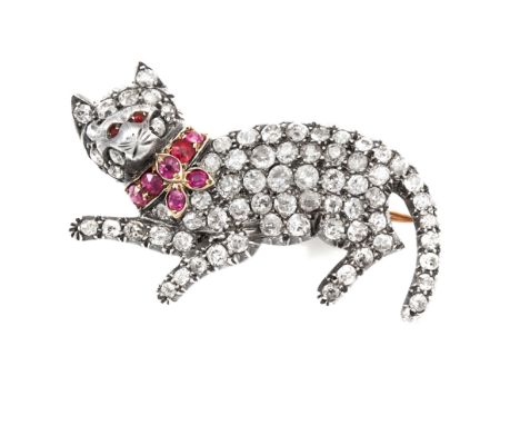 A DIAMOND AND RUBY CAT BROOCH in yellow gold and silver, designed as a recumbent cat, jewelled all over in round cut diamonds