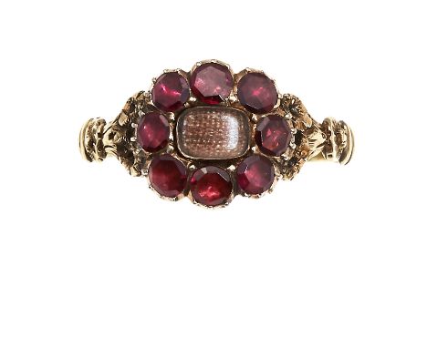 AN ANTIQUE HAIRWORK AND GARNET MOURNING RING in high carat yellow gold, set with a central panel of woven hairwork encircled 