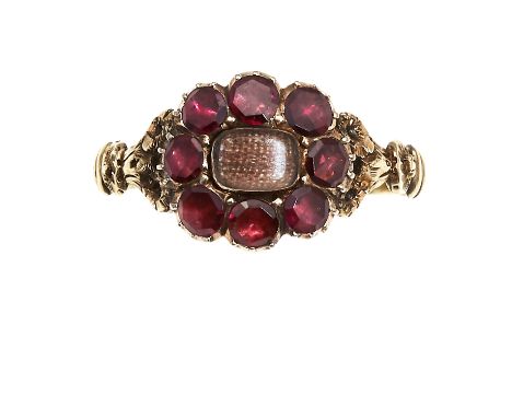 AN ANTIQUE HAIRWORK AND GARNET MOURNING RING in high carat yellow gold, set with a central panel of woven hairwork encircled 